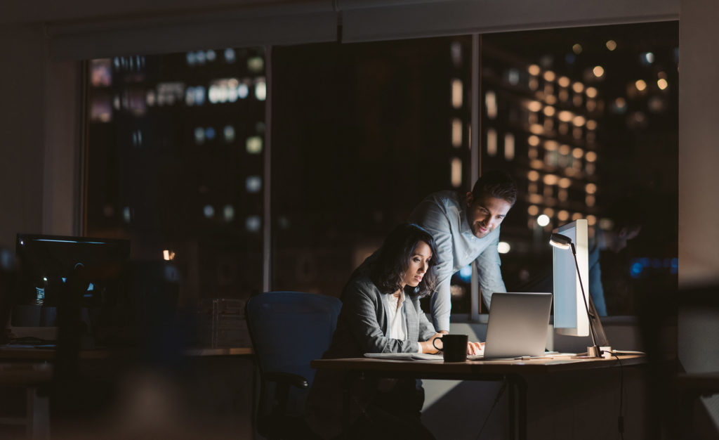 Man and woman staying at work late together focued